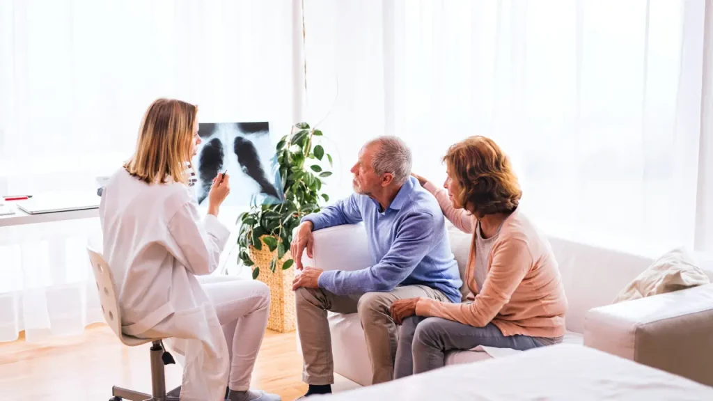Beyond the Diagnosis: Understanding How Pleural and Peritoneal Mesothelioma Develop Differently 1 Female doctor reviewing X-ray with a senior couple to explain mesothelioma development.