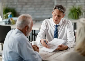 How Asbestos Trust Funds Are Calculated: Scheduled vs. Individual Review Explained 2 Veteran sitting at a table reviewing documents with a lawyer or claims adjuster.