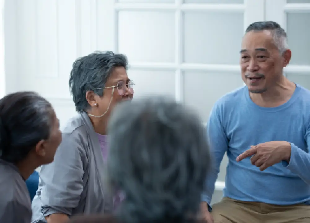 A group of seniors and caregivers talking and sharing information at a community health workshop.