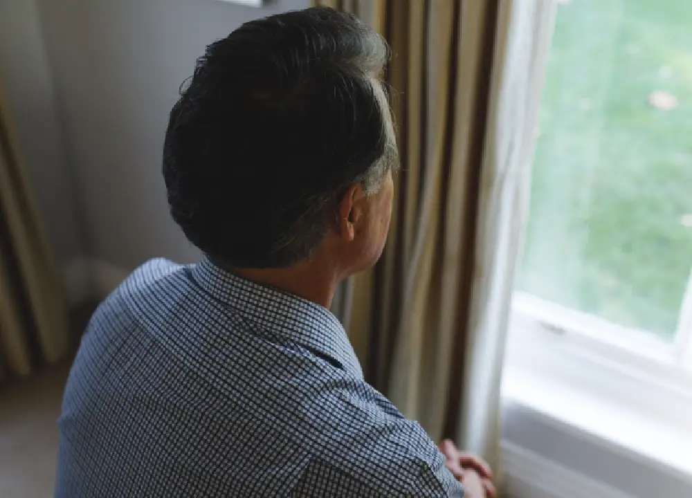 Mesothelioma Explained: Path to Justice and Compensation 3 Person looking out a window during a quiet moment of reflection.