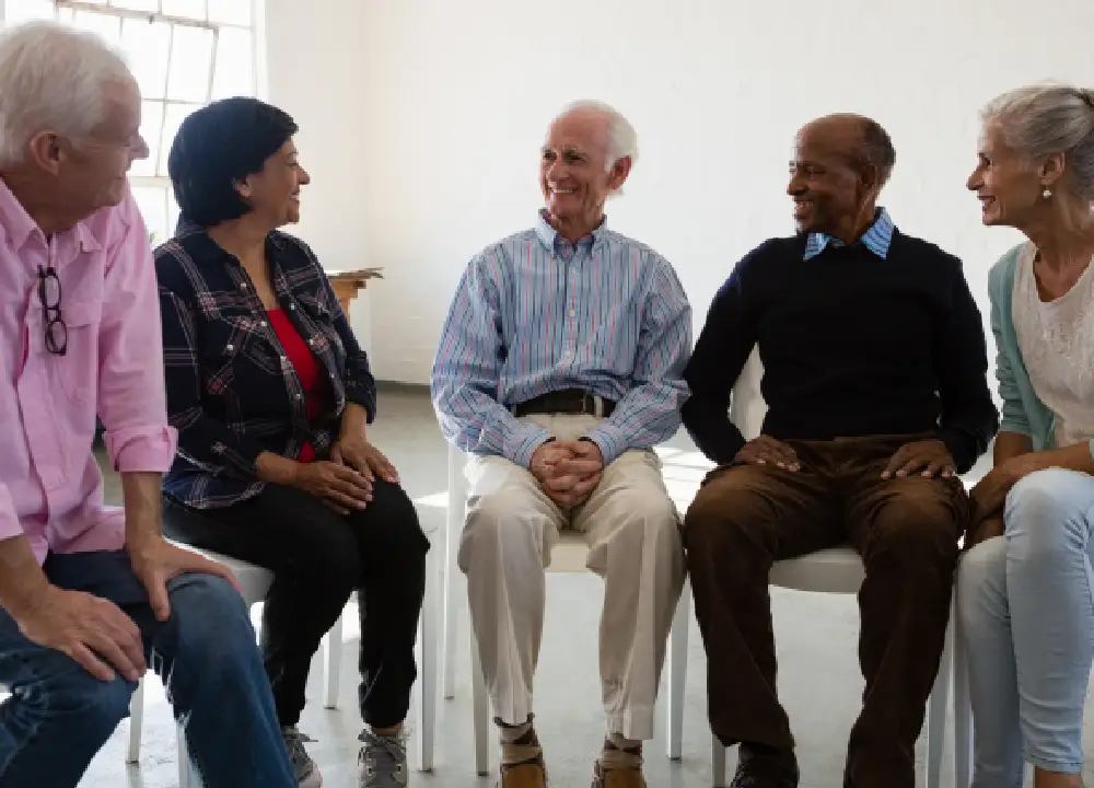 A diverse group of people sitting in a circle during a support group meeting in a bright, modern community center.