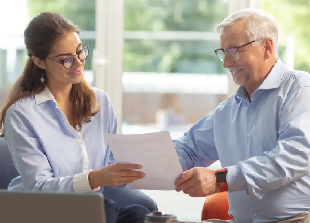 A supportive lawyer explaining legal documents to a senior man during a home visit.