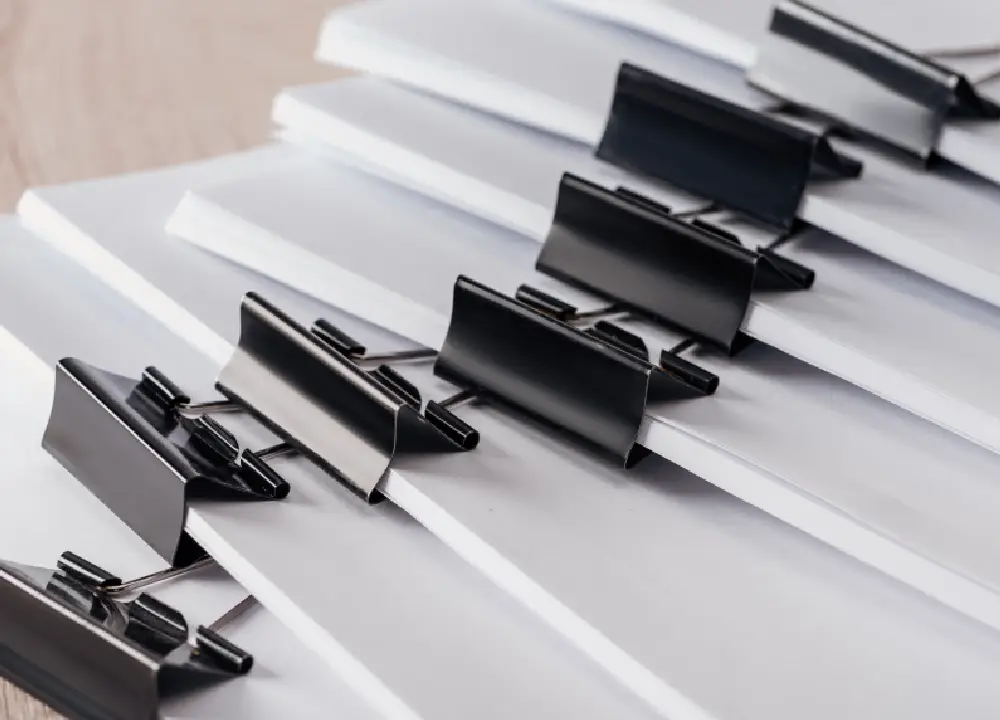 Mesothelioma Settlements vs. Lawsuits vs. Trust Funds 2 Close-up view of stacks of blank paper secured with metal binder clips.