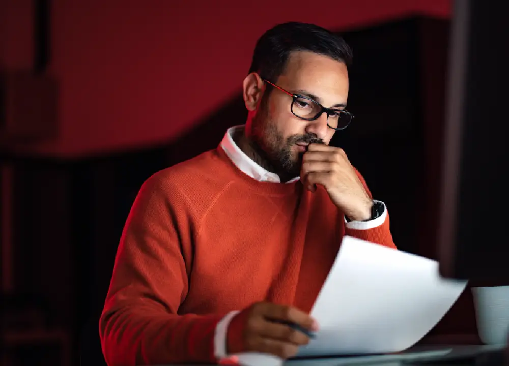 Navigating Asbestos Trust Fund Payments: A Victim’s Guide to Compensation 1 Person reviewing documents with a calm, focused expression.