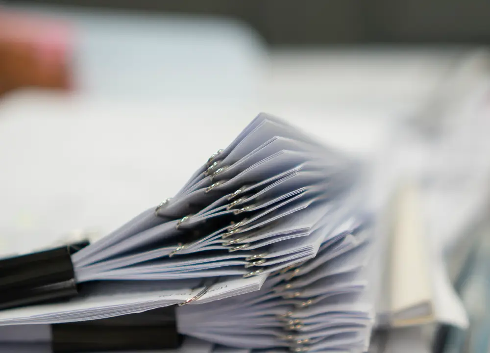 Navigating Asbestos Trust Fund Payments: A Victim’s Guide to Compensation 2 Stack of completed legal documents clipped together on a desk.
