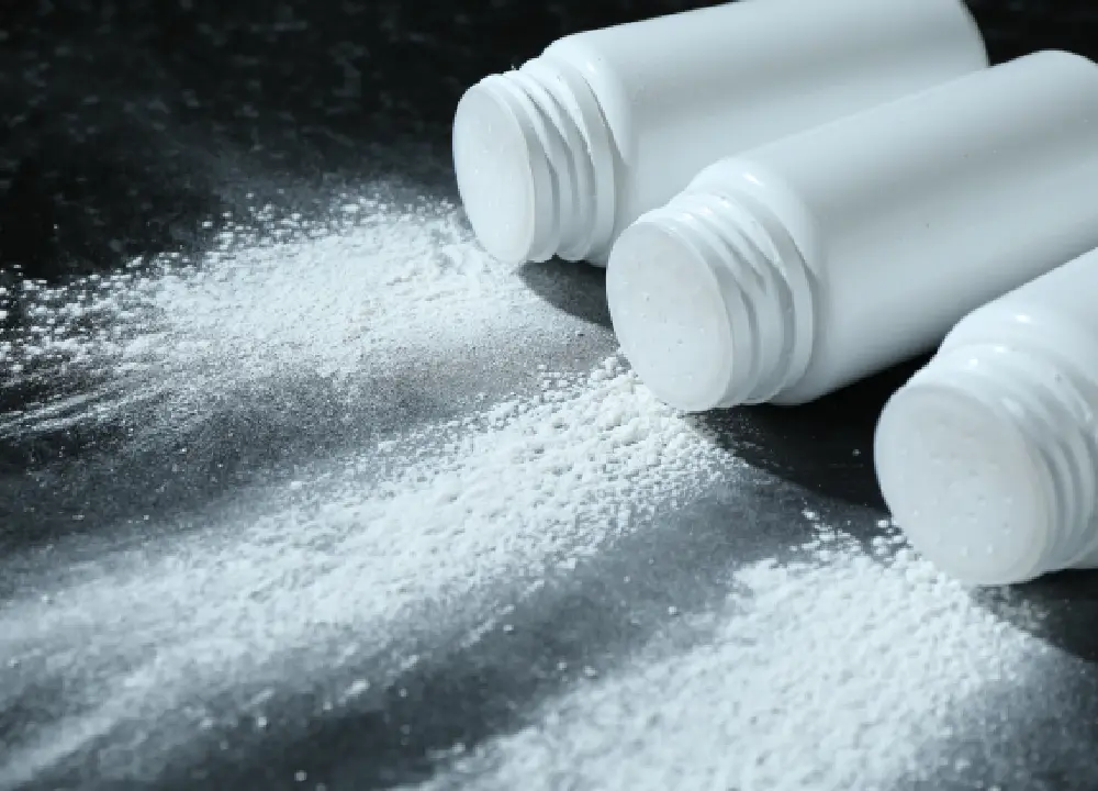 Your Guide to Talc and Asbestos Exposure Risks and Legal Options 1 Containers with talcum powder on a black table shown in close-up.