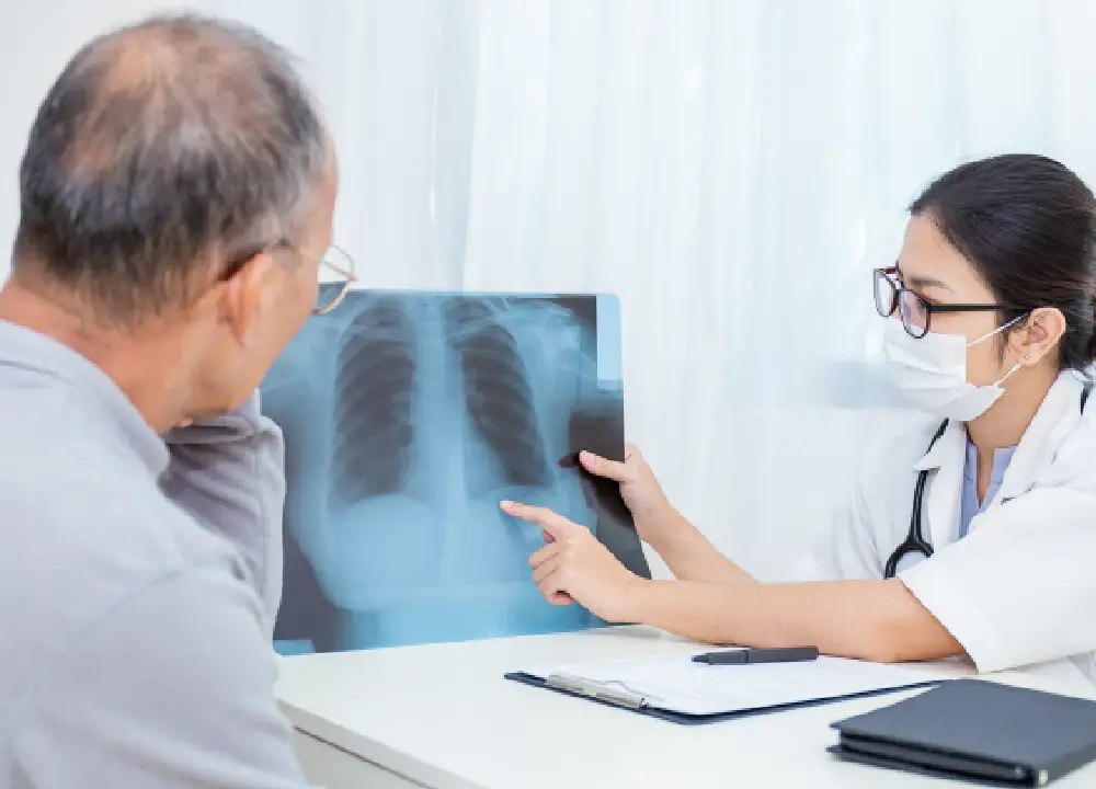 A doctor showing a senior patient a chest X-ray during a medical consultation for respiratory symptoms.
