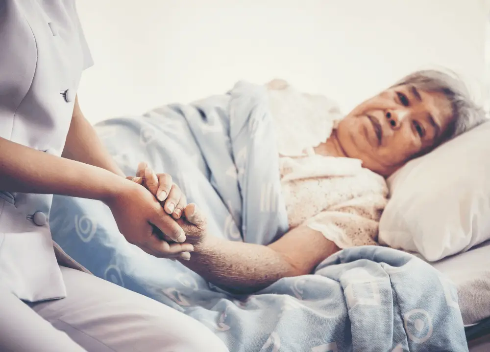 Hospice or palliative care nurse gently adjusting a patient’s pillow