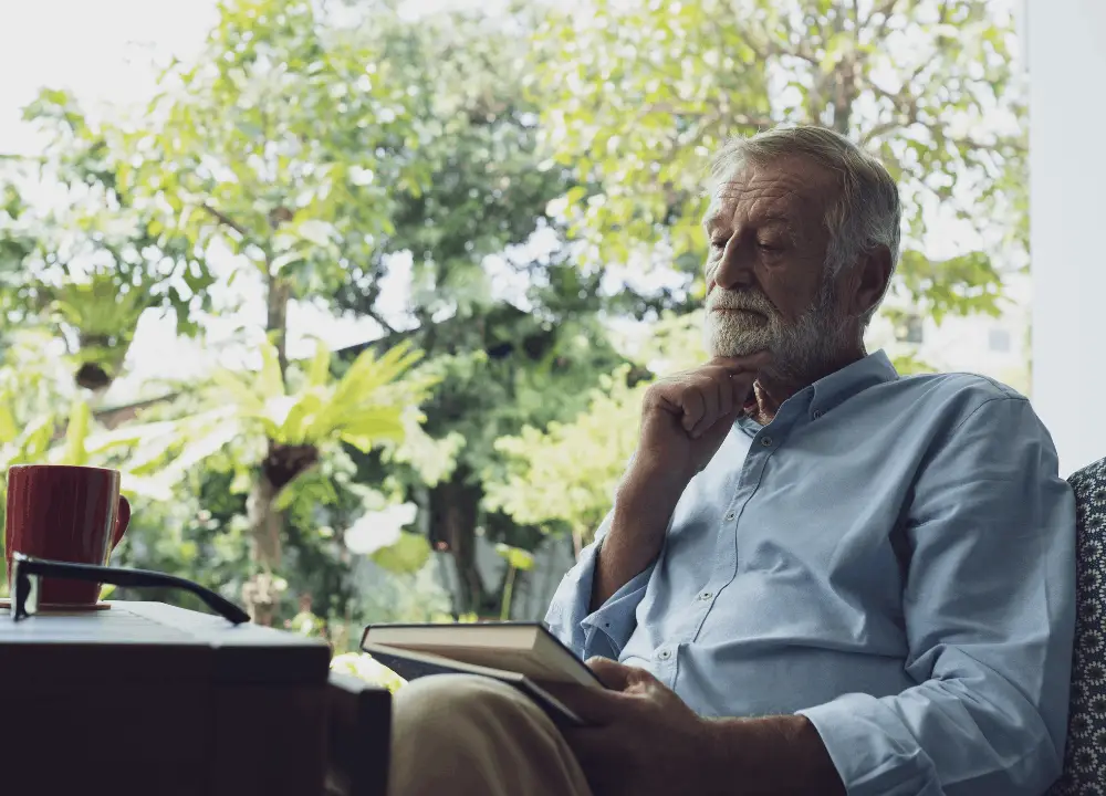 Person sitting by a window with a notebook, reflective and calm.