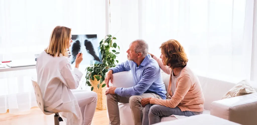 Female doctor reviewing X-ray with a senior couple to explain mesothelioma development.